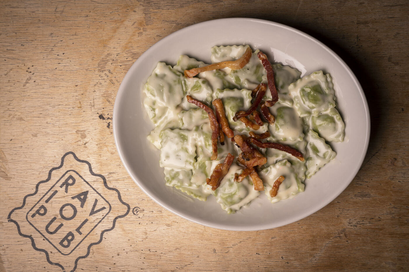 Ravioli con crema e pancetta croccante serviti su piatto RaviolPub